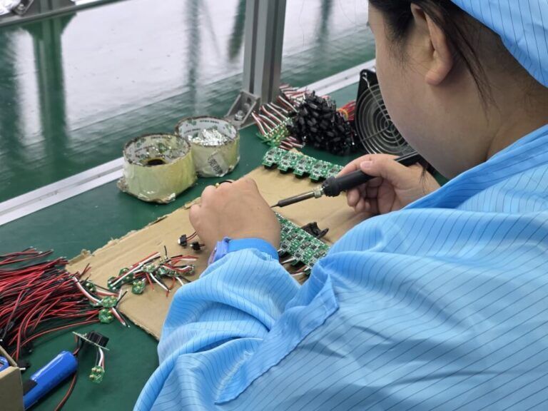 Close-up soldering work on a PCB inside a China factory.